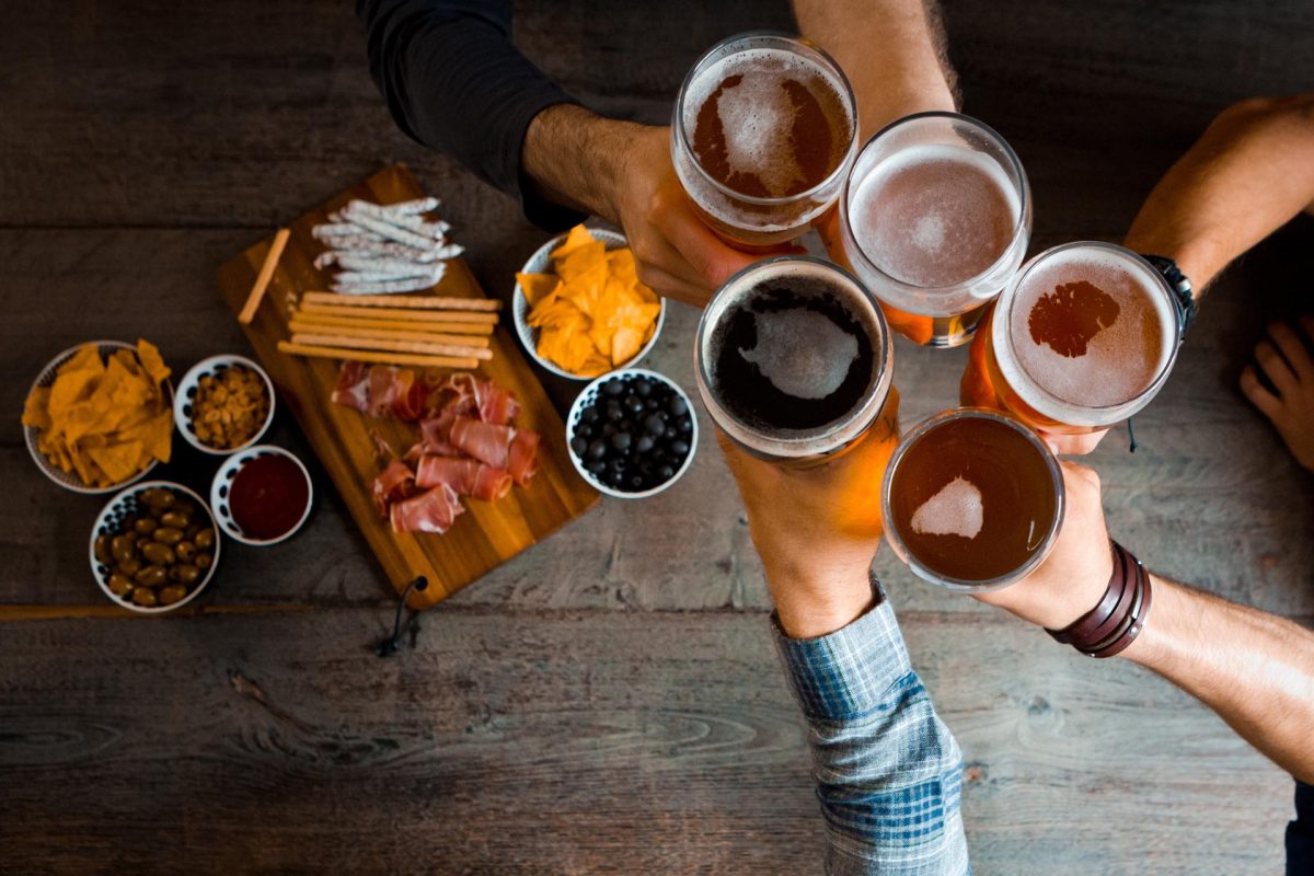 Top view of friends toasting with beer glasses in the pub. Unrecognizable people. High angle view of table.